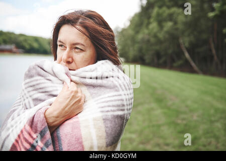 Reife Frau in ländlicher Umgebung, in der Decke eingewickelt Stockfoto