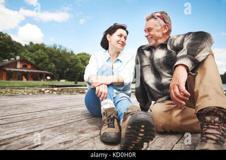 Reifes Paar entspannend auf Holzterrasse, lächelnd Stockfoto