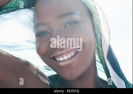 Porträt der jungen Frau am Strand, lächelnd, transparente Schal drapiert um Sie herum, close-up Stockfoto