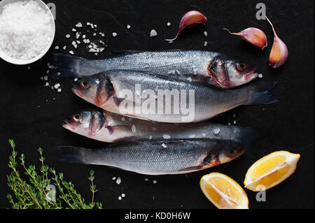 Rohe frische Fisch mit Zutaten auf dem schwarzen Stein Tabelle Stockfoto