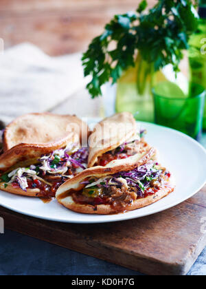 Zog Schweinefleisch, Krautsalat und Essiggurke gefaltet Pizza auf weiße Platte, close-up Stockfoto