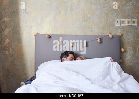 Paar im Bett, unter die Decke, küssen Stockfoto