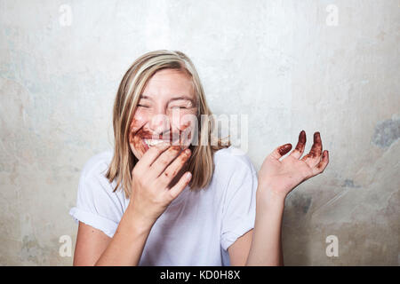 Portrait von Frau mit Schokolade an den Händen und um den Mund, Lachen Stockfoto