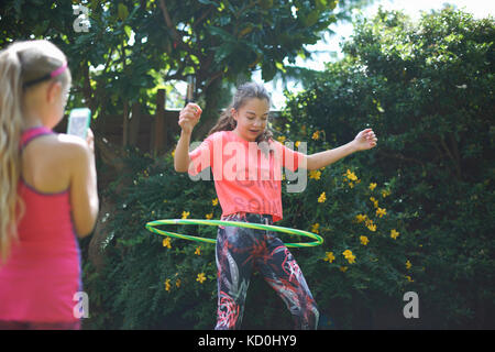 Mädchen fotografieren teenage Schwester hoola hooping in Garten Stockfoto