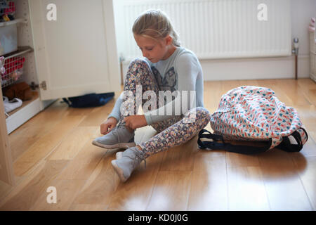 Mädchen sitzen auf Schlafzimmer, Schnürsenkel binden Beute Stockfoto