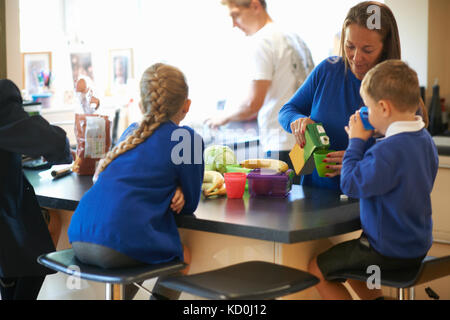 Mutter gießen Saft für Ihre Schule die Kinder in der Küche Stockfoto