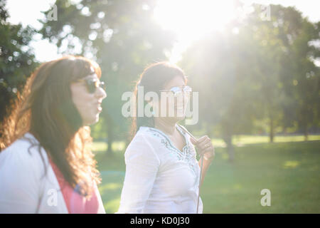 Zwei reife weibliche Freunde in sonnendurchfluteten Park, London, UK Stockfoto