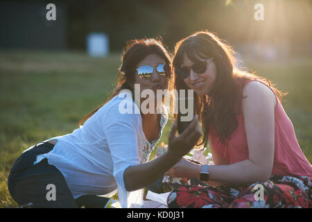 Zwei reife weibliche Freunde, Smartphone selfie bei Festival in Park, London, UK Stockfoto