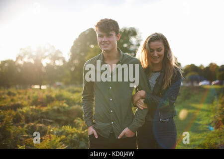 Junges Paar schlendern Arm in Arm im Feld Stockfoto