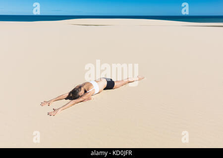 Frau am Strand liegend auf der Vorderseite in Yoga Position Stockfoto