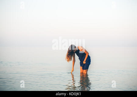 Junge Frau Knie tief im Meer berühren Oberfläche, Odessa, Ukraine Stockfoto