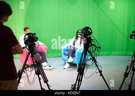 Junge männliche und weibliche Studenten üben im TV-Studio mit Green Screen Stockfoto