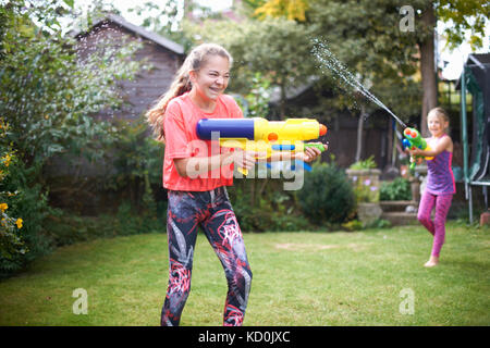 Teenager und ihre Schwester in Wasser Gun zu kämpfen, im Garten Stockfoto