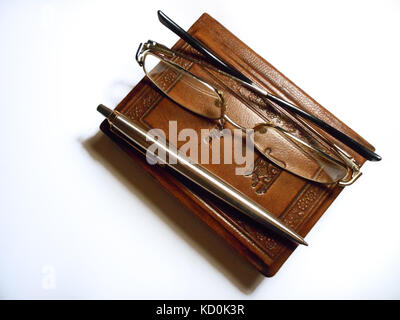 Ein geschlossenes kleines Buch mit Brille und ein Stift sitzen, Stockfoto