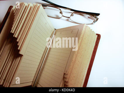 Eine geöffnete leeres Buch mit einem Stift auf es und Gläser auf der Seite Stockfoto