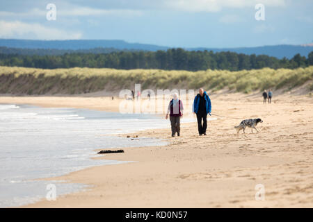 Wanderer geniessen Herbst Sonne auf den Sandstrand an der malerischen Badeort Lossiemouth, Schottland Stockfoto