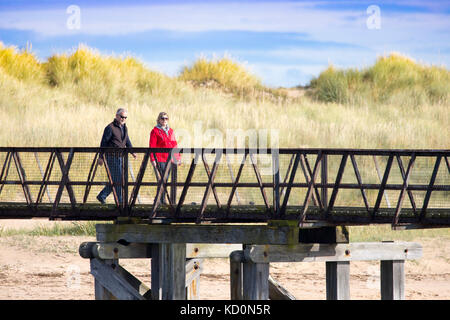 Lossiemouth, Großbritannien. Mit Schauerwetter aus dem Weg Es war ein warmer und sonniger Tag an der Küste von Lossiemouth, Schottland wie dieses Paar entdeckt Rückkehr vom Strand über die Fuß-Brücke Stockfoto