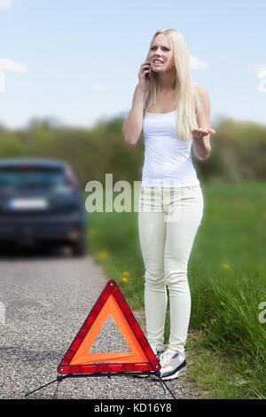 Porträt der jungen Frau um Hilfe, Auto zu reparieren Stockfoto