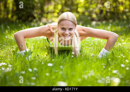 Porträt der jungen blonden Frau Doing Push-Ups Stockfoto