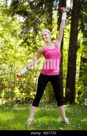 Junge Frau mit Hanteln für Training im Park Stockfoto