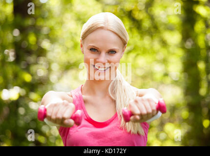 Junge Frau mit Hanteln für Training im Park Stockfoto