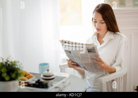 Junge schöne Frau lesen Magazin am Tisch Stockfoto