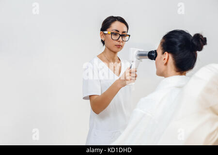 Weibliche optometrist mit spezieller Ausrüstung überprüfen patient Vision bei Augenklinik. Augenarzt Messung des Augeninnendrucks der jungen Frau in clin Stockfoto