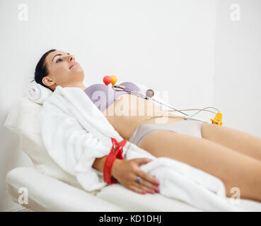 Weibliche Patienten mit EKG Elektrokardiogramm im Krankenhaus. Frau Patient liegt in einem weißen Mantel mit EKG-Geräten, Elektrokardiogramm testen. Stockfoto