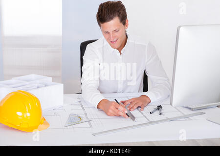 Portrait eines glücklichen jungen Architekten Zeichnung plan auf Blueprint Stockfoto