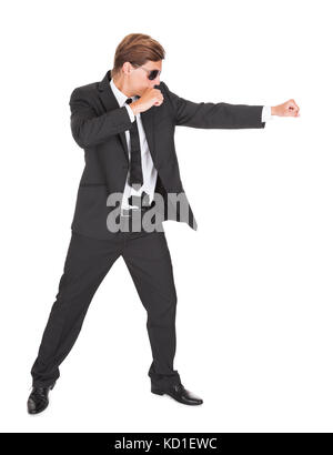 Junger Mann im schwarzen Anzug Stanzen auf weißem Hintergrund Stockfoto