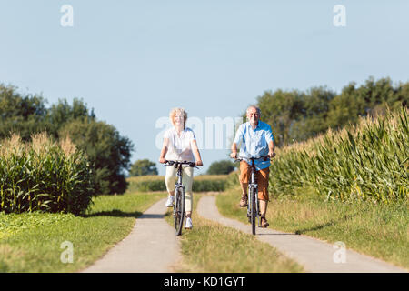 Senior Paar freuen uns mit Vertrauen beim Reiten bicyc Stockfoto