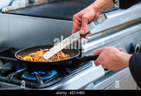 Koch drehen Fisch in der Pfanne beim Kochen Stockfoto