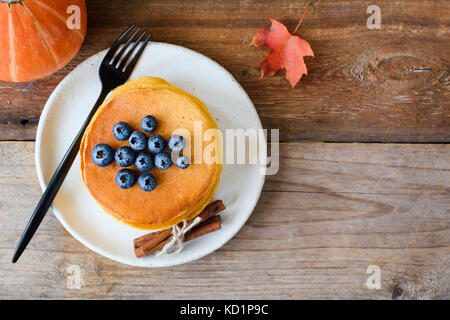 Kürbis Pfannkuchen mit Heidelbeeren und Honig auf weiße Platte über alten Holztisch. table top anzeigen, kopieren Platz für Text Stockfoto