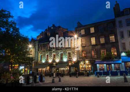 Edinburgh, Schottland - September 25, 2017: Lit grassmarket Pubs mit Edinburgh Castle im Hintergrund, während blaue Stunde Stockfoto