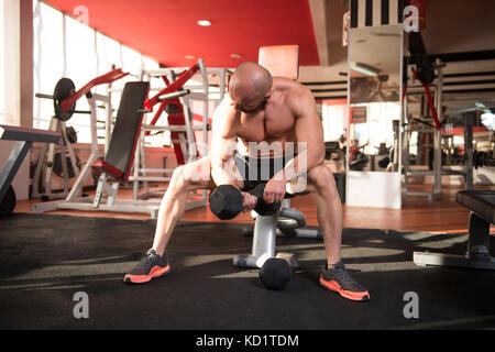 Man Working Out Bizeps In einem Fitnessstudio - Hantel Konzentration locken Stockfoto