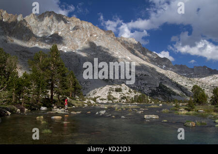 Ein Wanderer Hopfen über Steine auf Evolution Creek entlang der John Muir Trail in Kings Canyon National Park Kalifornien Stockfoto