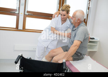 Physiotherapeut Holding älterer Patienten vor dem Rollstuhl Stockfoto