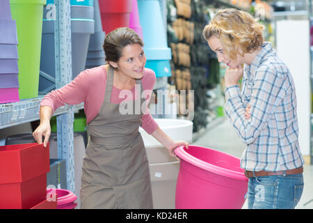 Shop Assistant hilft Kunden große Kunststoff Pflanzmaschine wählen Stockfoto