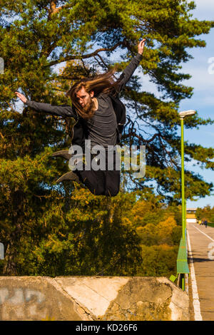Stylisches junger Mann mit langem Bart und lange Haare, springt von der Brücke sonnigen Tag im Sommer. Stockfoto