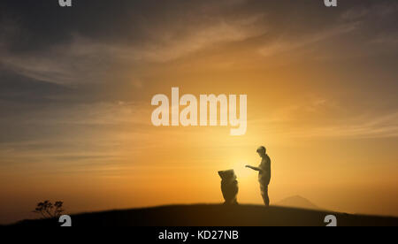 Futuristisches Konzept, silhouette Mann legte eine Hand auf Befehl der Roboter (Künstliche Intelligenz) oben auf dem Berg mit Sonnenuntergang im Hintergrund und Stockfoto