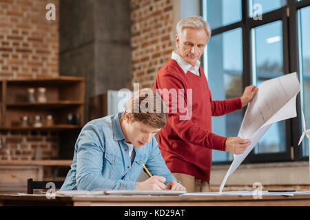 Älterer Mann seine Blaupause im Vergleich zu seinen Kollegen ein Stockfoto