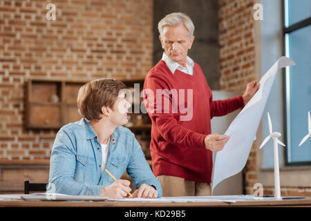 Ältere erfahrene man Kontrolle Blaupause von seinen jungen Kollegen Stockfoto