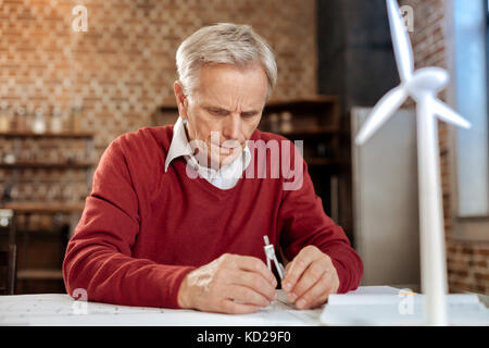 Ernsthafte älterer Mann mit einem Zirkel Stockfoto