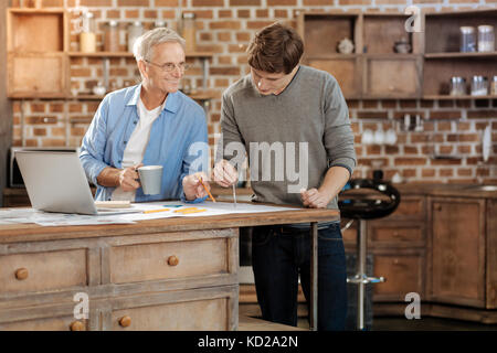 Älterer Mann seinen jungen Kollegen Beratung über Zeichnung geben Stockfoto