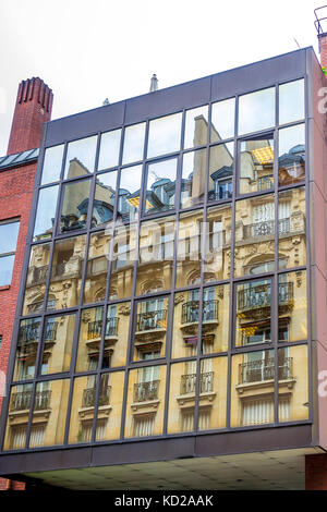 Schöne Apartments in einer Pariser Straße spiegeln sich in modernen Fenstern wider. Stockfoto