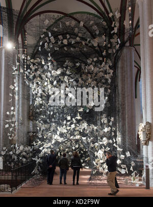 Besucher in der Kunstinstallation „Lost Words“ des japanischen Künstlers Chiharu Shiota in der Nikolaikirche in Berlin, Deutschland, 09. Oktober 2017. 750 Kilometer lange Fäden und 4000 Seiten aus der Bibel in 100 Sprachen wurden in einem einzigen Werk im Mittelschiff der Kirche verwoben. Das riesige Spinnennetz kann bis zum 19. November 2017 besucht werden. Foto: Paul Zinken/dpa Stockfoto