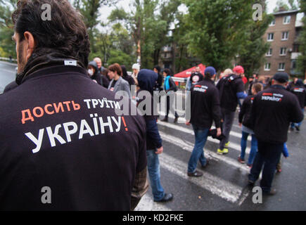 Kryvyi Rih, Ukraine - 9. Oktober 2017: Menschen in T-Shirts mit der Aufschrift „Stop to Poison Ukraine“ blockieren die Fahrbahn während des Protesttreffens in der Nähe des ArcelorMittal Kryvyi Rih PJSC behaupten, die Luftverschmutzung zu reduzieren und eine unabhängige Prüfung der Reinigungsausrüstung in der Stahlfabrik durchzuführen Stockfoto