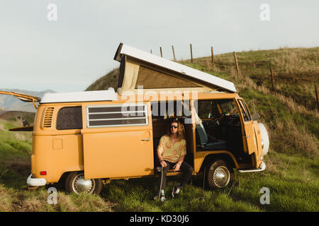 Junge männliche Skateboarder auf der Suche von Vintage recreational vehicle, Exeter, Kalifornien, USA Stockfoto