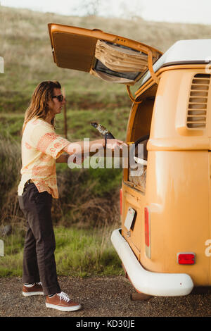 Junge männliche Surfer Surfbrett aus Vintage recreational vehicle, Exeter, Kalifornien, USA Stockfoto