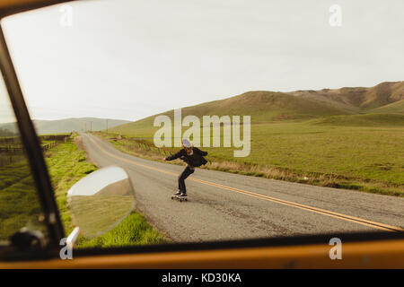 Auto Fenster mit Blick auf junge männliche Skateboarder skaten entlang der ländlichen, Exeter, Kalifornien, USA Stockfoto